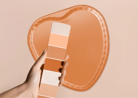 Vor einer herzförmigen Backform in orange wird eine Karte einer Farbpalette in Orangetönen gezeigt. 