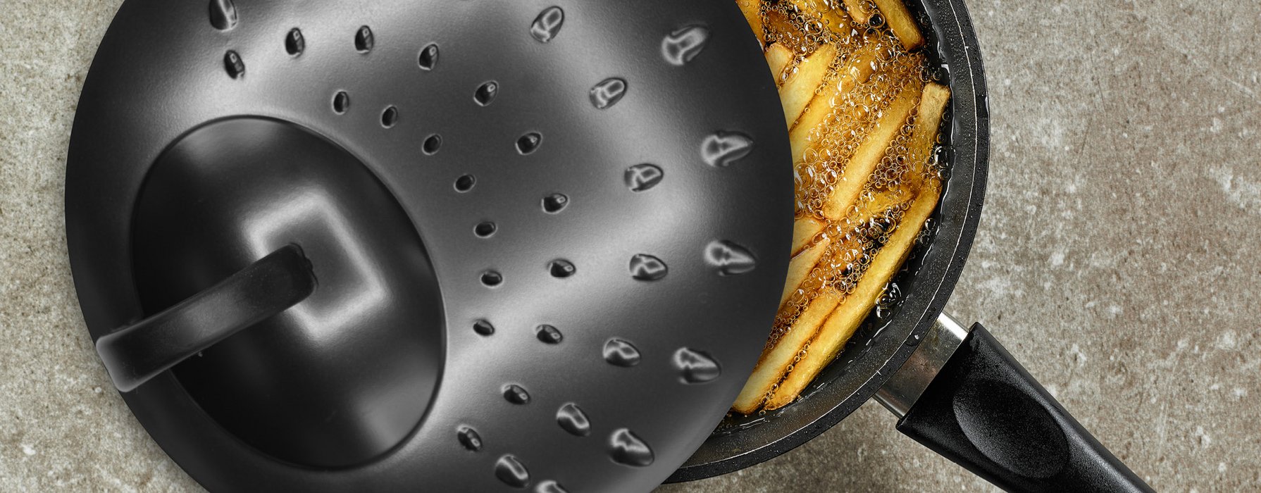 Black splash guard lid of a pan on a pot with fries in hot oil