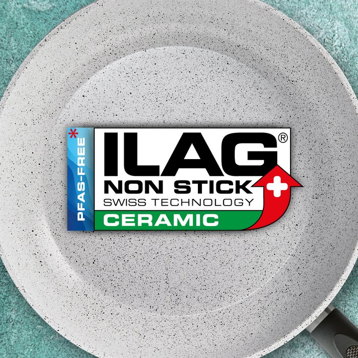 Weisse,mit schwarzen feinen Punkten versehene, Innenseite einer Bratpfanne - mittig das ILAG Logo mit dunkelgrün unterlegtem Ceramic Schriftzug und links zusätzlicher Beschriftung "PFAS-FREE" in blau»