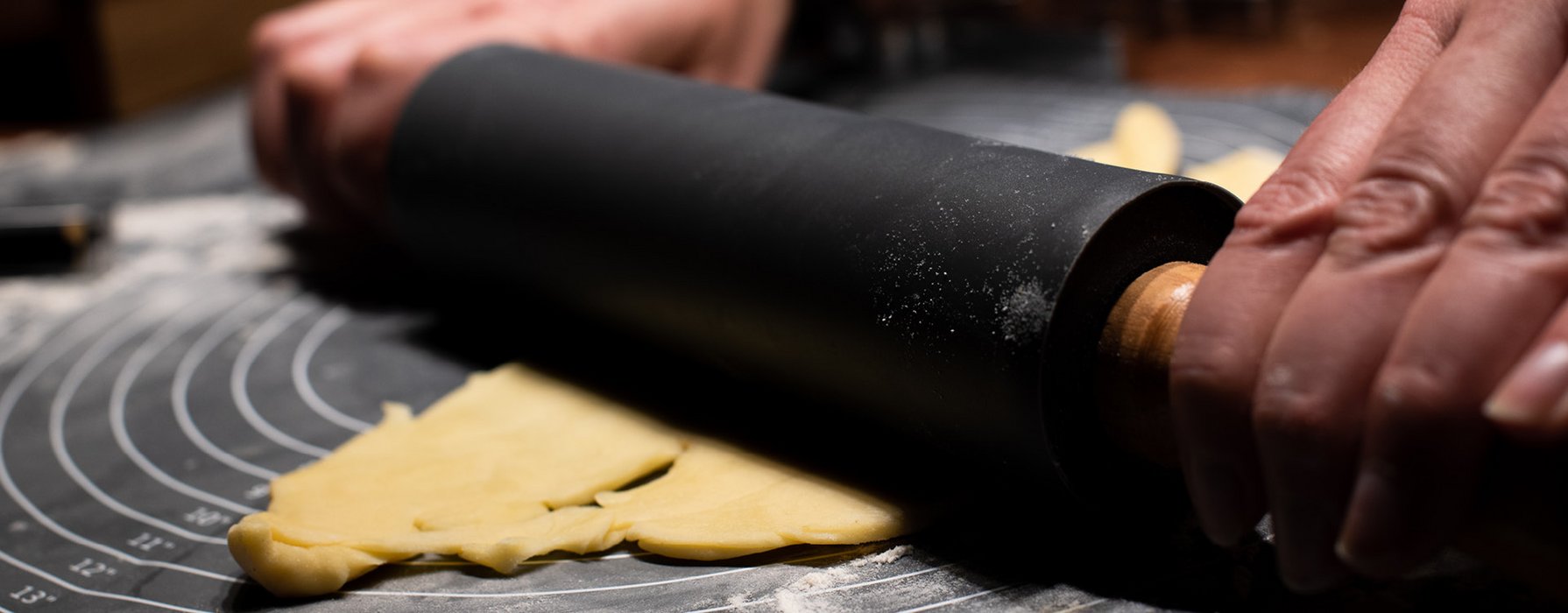 Black coated rolling pin rolls a dough flat