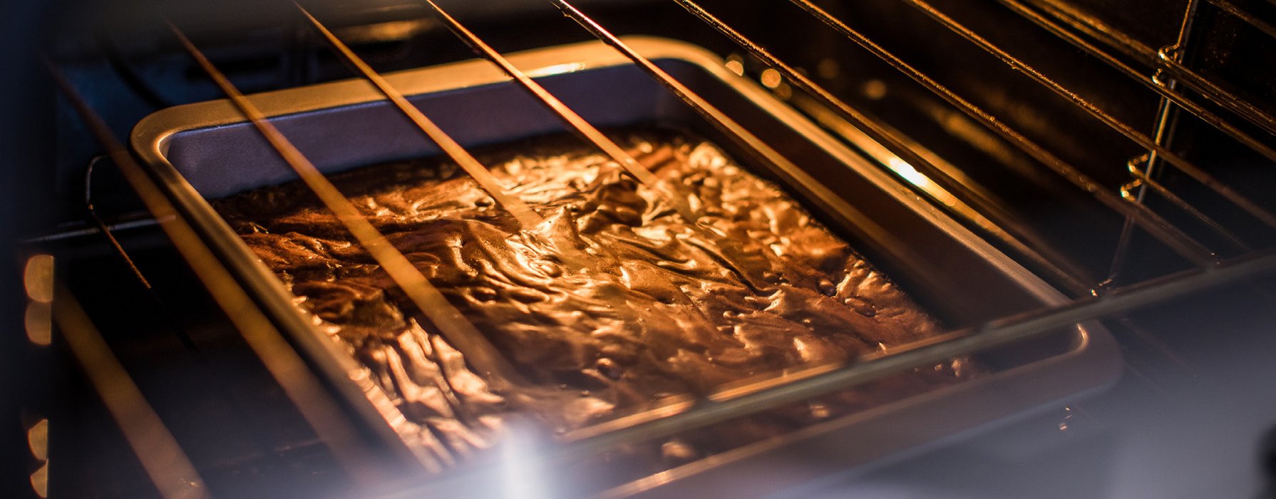 Chocolate dough in a square casserole dish is baking in the oven. 