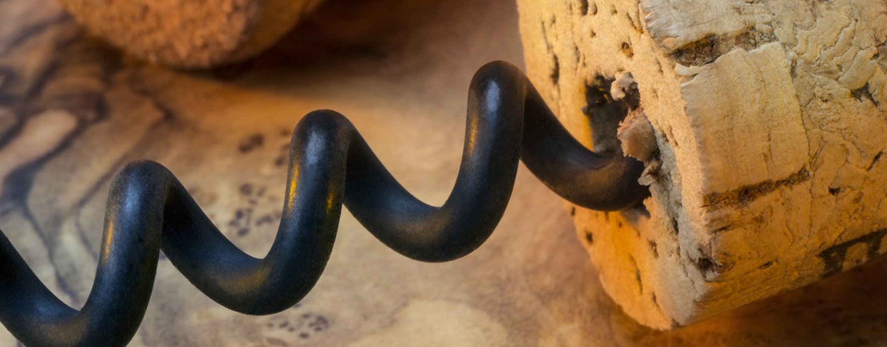 Close-up view of a black coated screw which sticks in a wine cork 