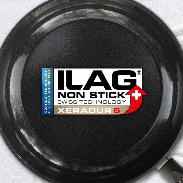 Schwarz glänzende Innenseite einer Bratpfanne - mittig das ILAG Logo mit beige unterlegtem Xeradur 5 Schriftzug und links zusätzlicher Beschriftung "PFAS-FREE" in blau