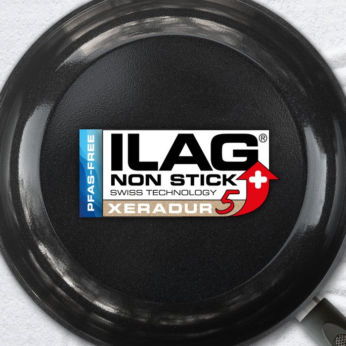 Schwarz glänzende Innenseite einer Bratpfanne - mittig das ILAG Logo mit beige unterlegtem Xeradur 5 Schriftzug und links zusätzlicher Beschriftung "PFAS-FREE" in blau
