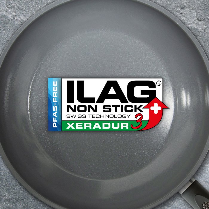 Grau glänzende Innenseite einer Bratpfanne - mittig das ILAG Logo mit dunkelgrün unterlegtem Xeradur 3 Schriftzug und links zusätzlicher Beschriftung "PFAS-FREE" in blau