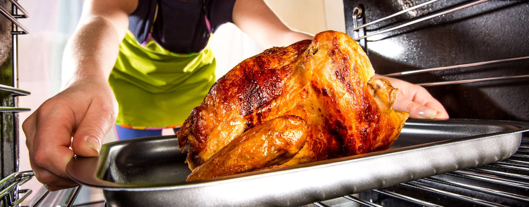 Grilled chicken on a baking tray is taking out of an oven